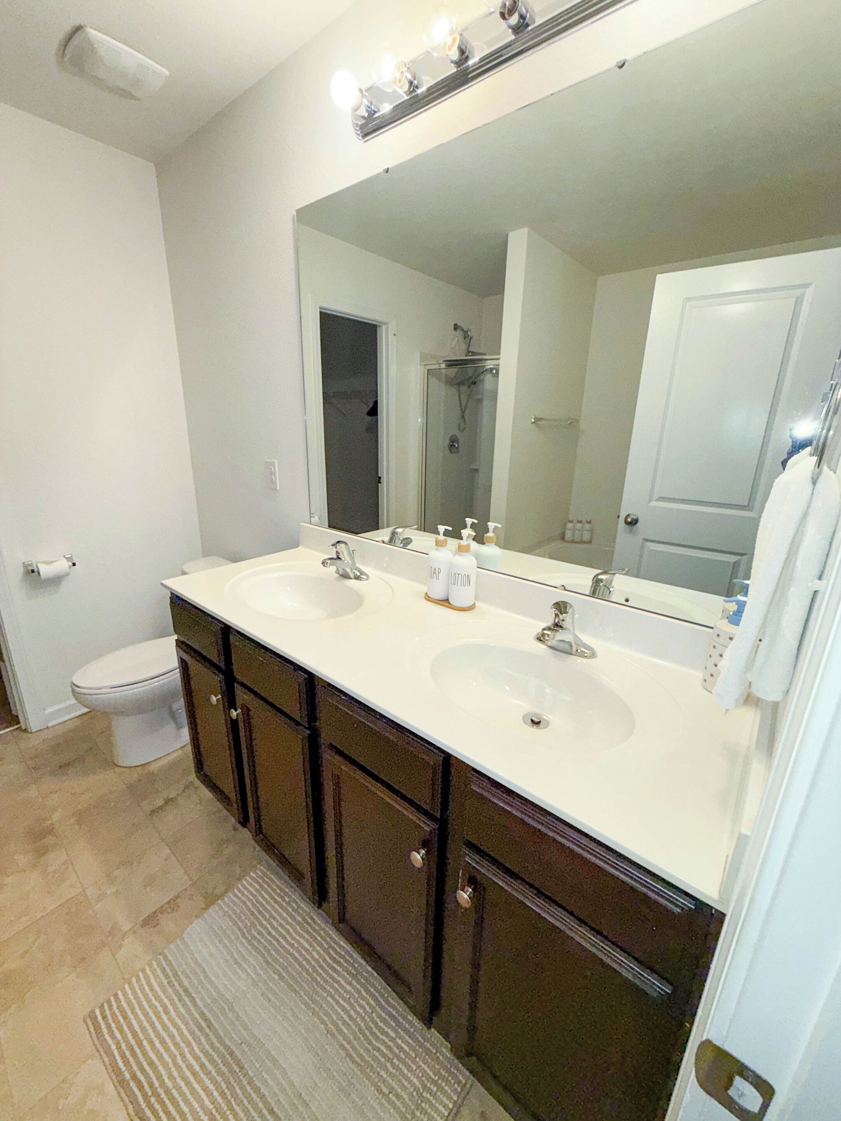 A bathroom with two sinks, a large mirror, and a shower.