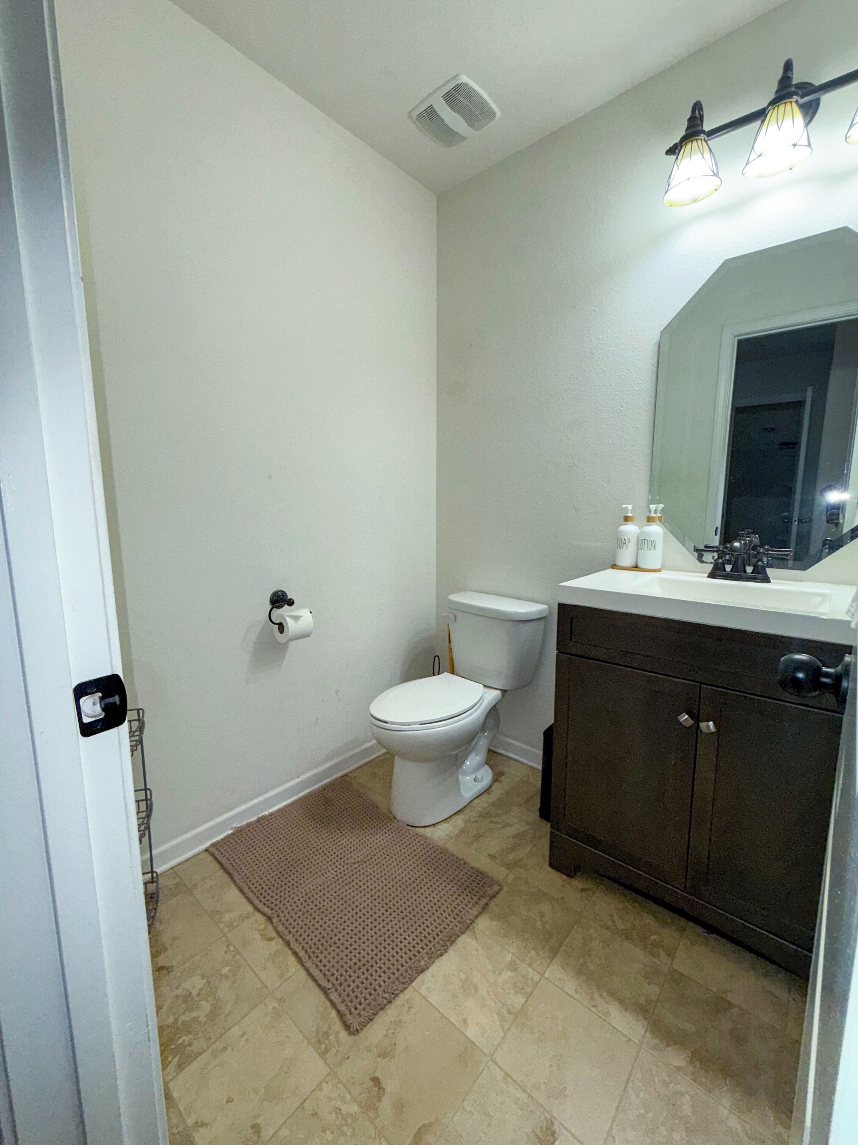 A small bathroom with a toilet, a sink, and a mirror.