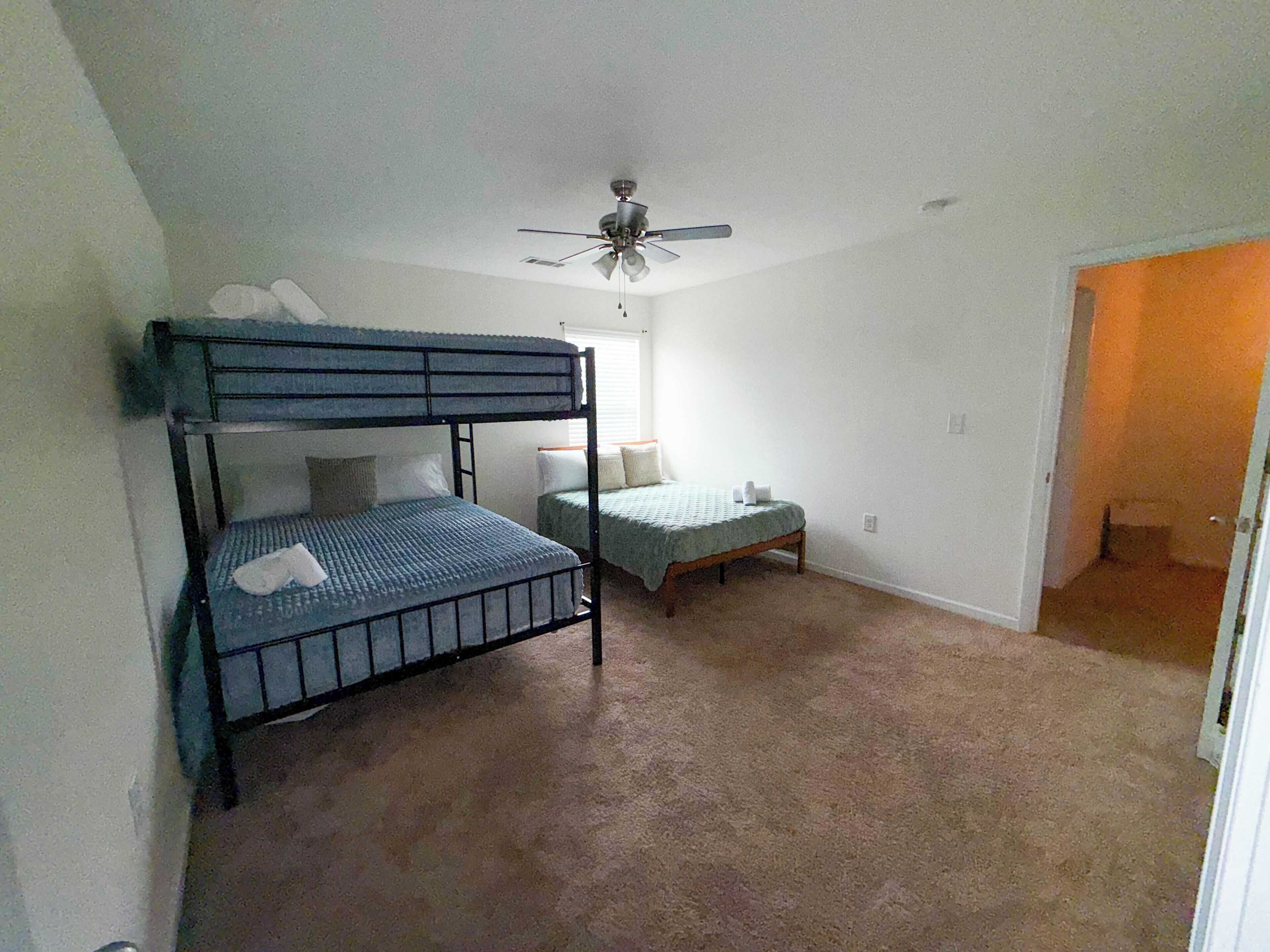 A bedroom with bunk beds, a ceiling fan, and a carpeted floor.