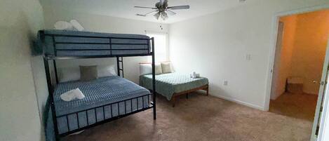 A bedroom with bunk beds, a ceiling fan, and a carpeted floor.