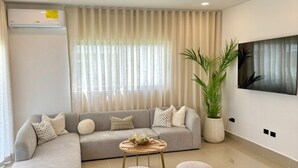 A modern living room with a sectional sofa, a coffee table, and two ottomans. - Brand-New 4BR with 5 beds Home in Bávaro Punta Cana-Private Pool (Punta Cana)