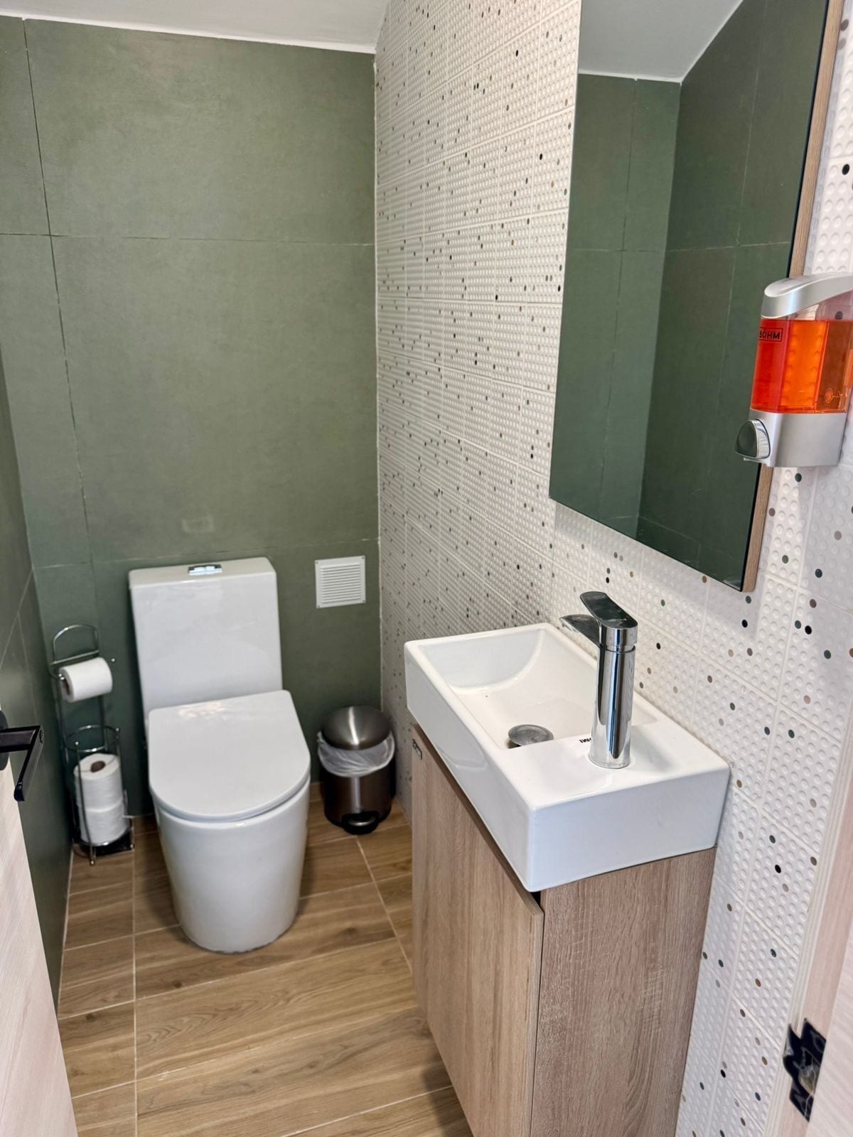 Ein kleines Badezimmer mit Toilette, Waschbecken und Spiegel.
