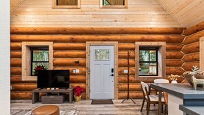 A log cabin interior with a television, seating area, and a dining space. - Log Cabin! Hot Tub! Firepit! 5 mi Mt Rainier NP! (Ashford)