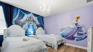 Une chambre avec deux lits, un lustre, une fresque représentant un château et une commode.