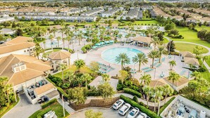 Vista aérea de un resort con piscina central, varias zonas de descanso y abundante vegetación.