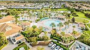 Luftaufnahme eines Resorts mit einem zentralen Pool, mehreren Liegebereichen und umliegender Bepflanzung.