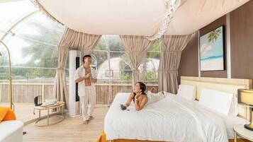 A bedroom with a large bed, a bedside table, a lamp, and a view through the window.