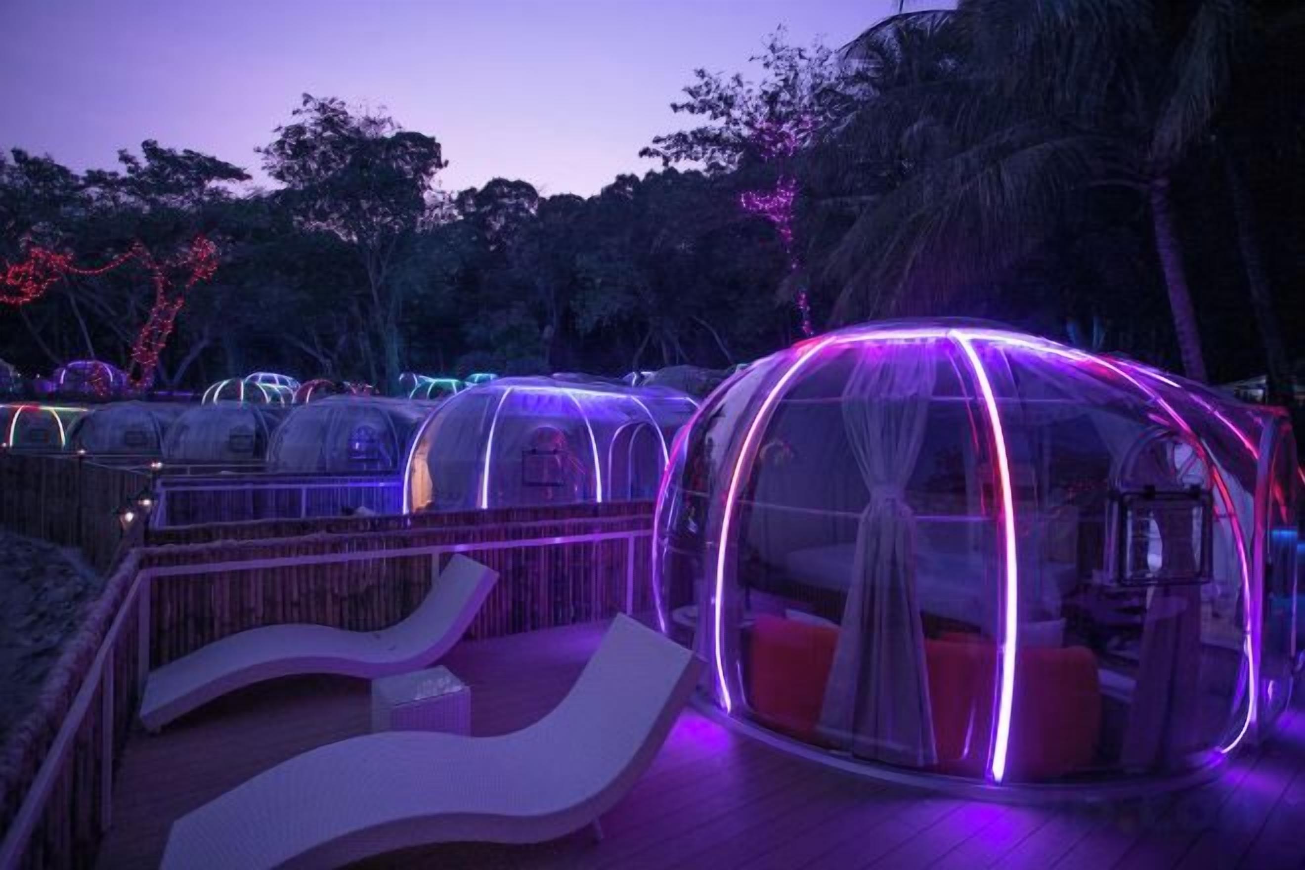 Transparent dome-shaped accommodations with seating areas in front.