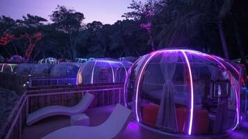 Transparent dome-shaped accommodations with seating areas in front.