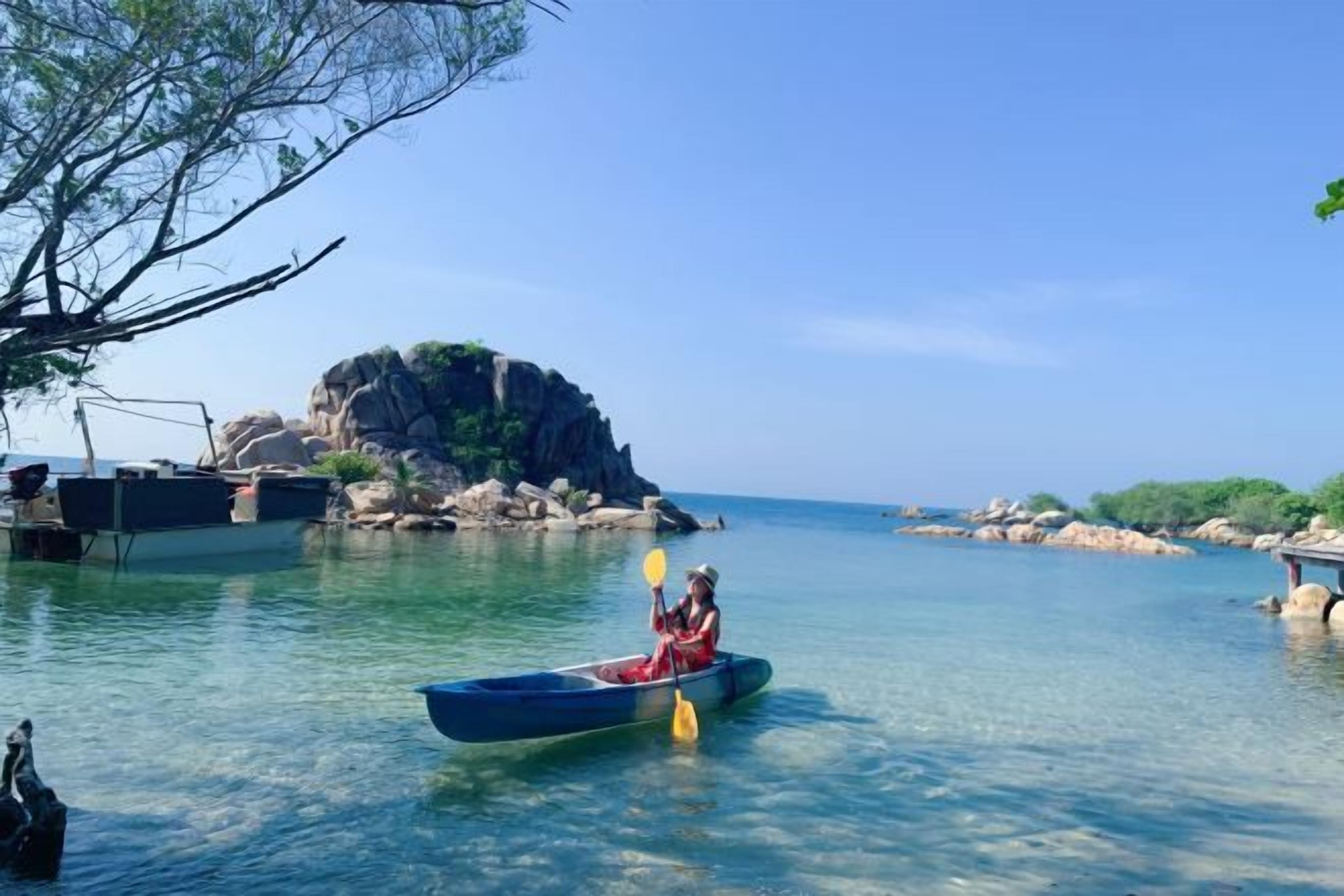 A calm body of water with a single canoe and a person paddling.