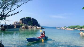 A calm body of water with a single canoe and a person paddling.