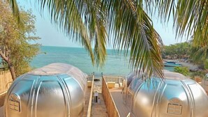Deux structures métalliques en forme de dôme offrent une vue sur la mer et sur les palmiers qui se dressent à l’arrière-plan.