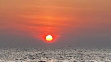 A sunset over the ocean with calm water and a clear sky.