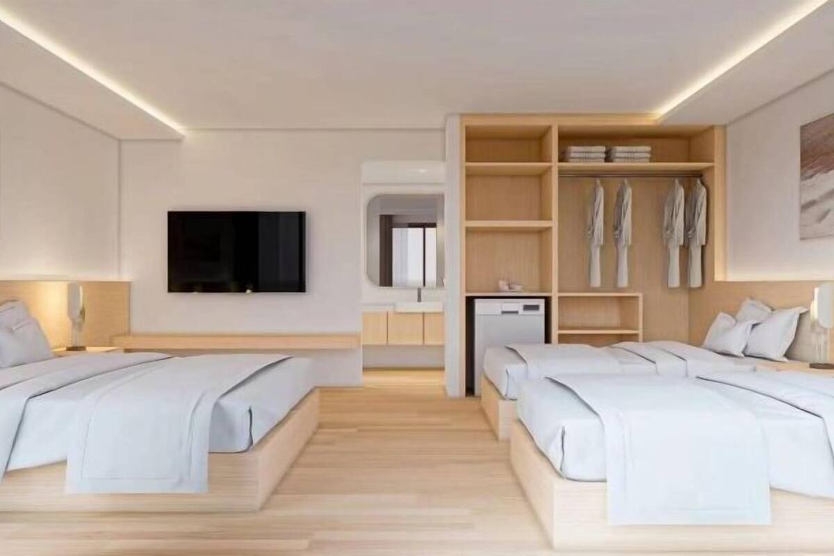Ein Hotelzimmer mit zwei Betten, einem Fernseher, einem Schreibtisch und einem Kleiderschrank.
