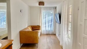 Un salon moderne avec un canapé, un plancher en bois et un téléviseur fixé au mur.