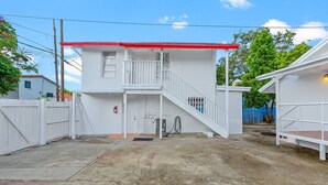 Un bâtiment à deux étages, avec un toit rouge, un balcon et un escalier menant à l’étage supérieur.