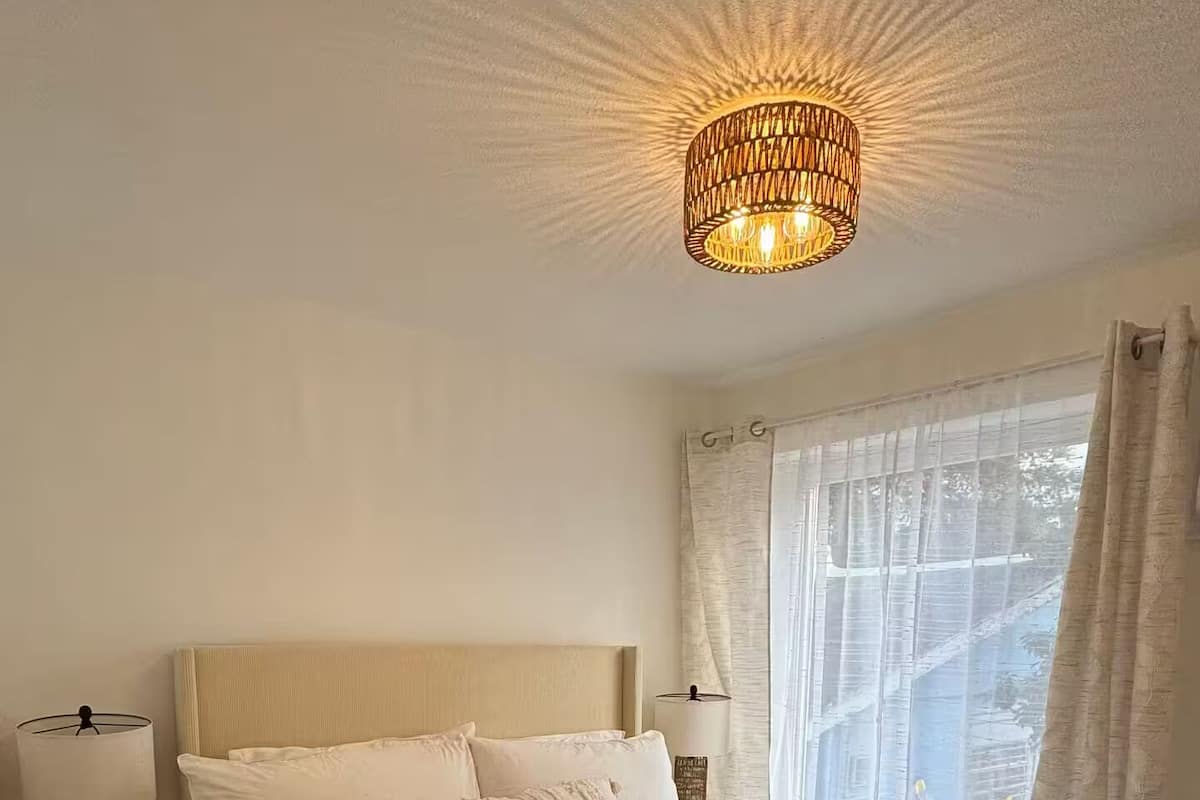 Une chambre à coucher avec un grand lit, une table de chevet avec une lampe et un luminaire au plafond.