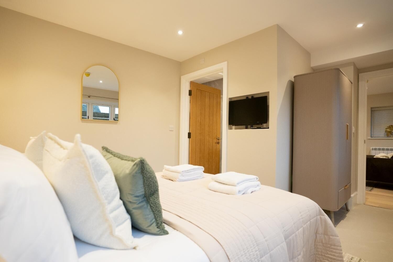 A hotel room with a bed, pillows, a TV, and a wardrobe.