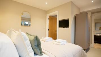 A hotel room with a bed, pillows, a TV, and a wardrobe.