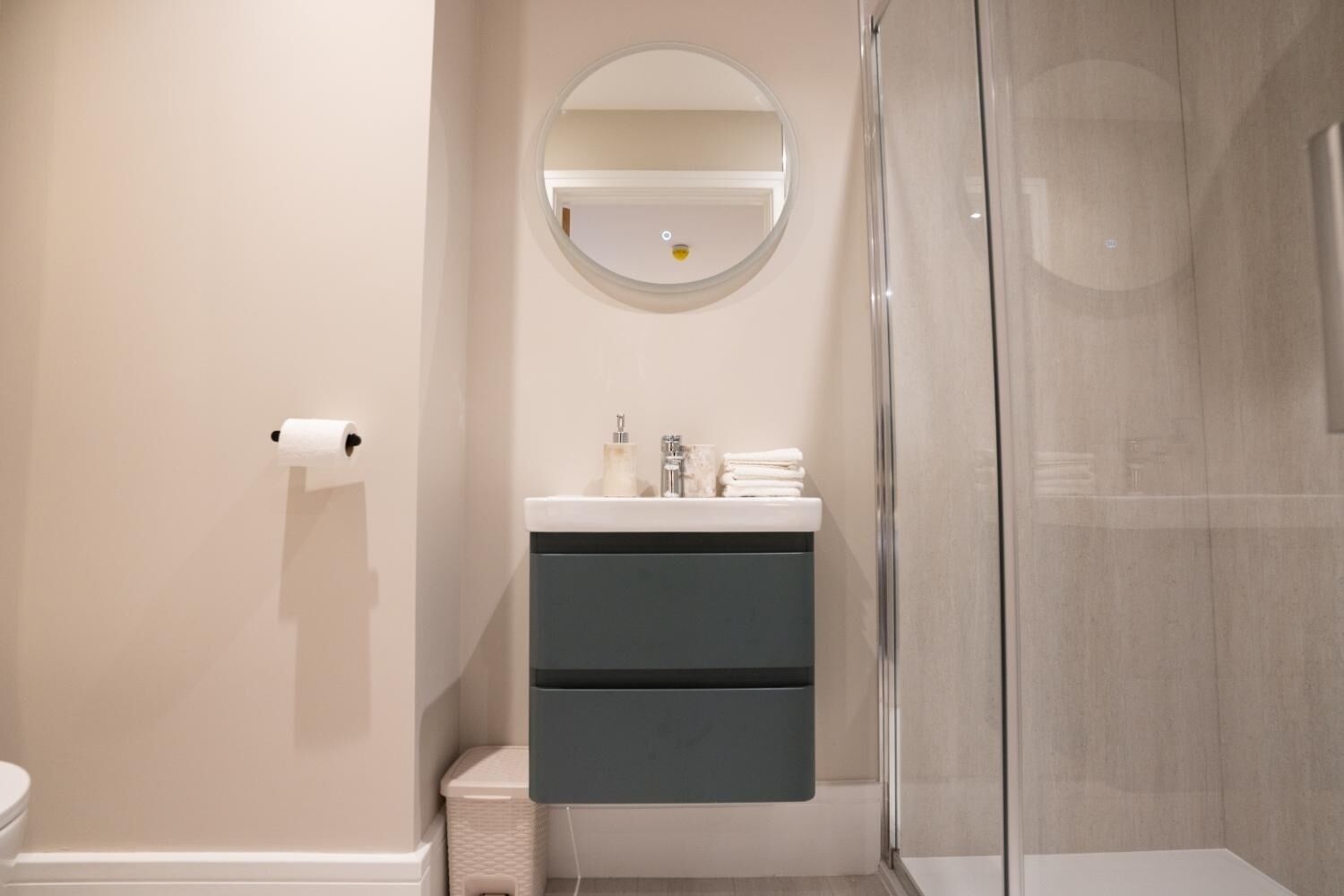 A modern bathroom with a toilet, a sink with a mirror above it, and a glass shower enclosure.