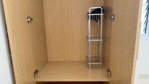 Un armario de madera con un estante metálico en su interior.