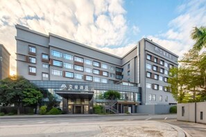 A multi-story hotel with a modern architectural design, featuring a prominent entrance with a glass facade and a covered area. - Aifeel Hotel (Zhuhai Gongbei Port） (Zhuhai)