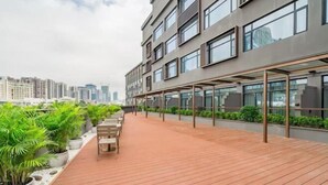 Una terrazza sul tetto con piante in vaso, posti a sedere e vista sullo skyline della città.
