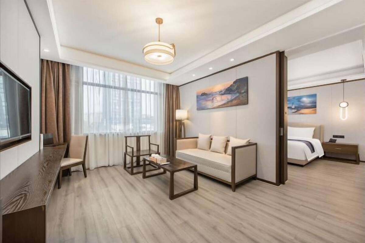 Ett modernt hotellrum med en soffa, ett litet bord, en TV och en tavla på väggen.