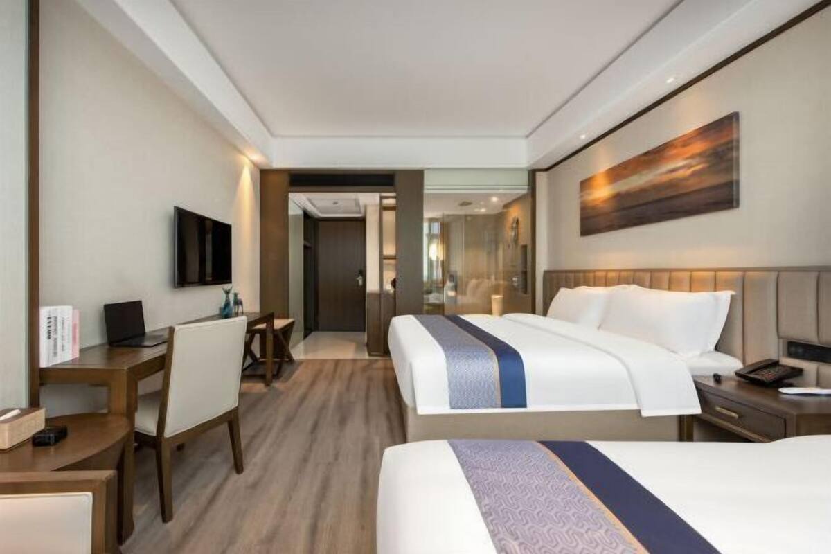 Ett hotellrum med en säng, ett skrivbord, en stol och en tv.