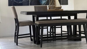 A dining area with a modern table and chairs, a large abstract painting, and a hanging light fixture. - Beautiful and modern single home located 5 minutes from Indian Rocks Beach . (Largo)