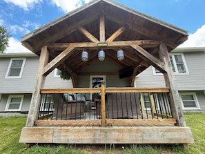 A wooden porch with a railing, a bench, and a hanging plant.