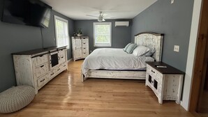A bedroom with a bed, dresser, nightstand, ceiling fan, and a TV mounted on the wall. - Charming 4-bedroom house with a big yard in Poultney (Poultney)