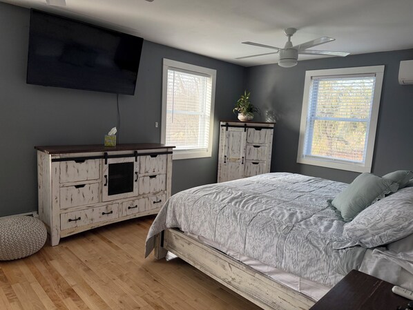 A bedroom with a bed, a dresser, a television, and a ceiling fan.