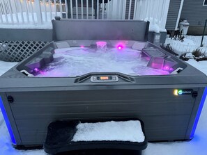 A hot tub with a control panel and a snow-covered ground.