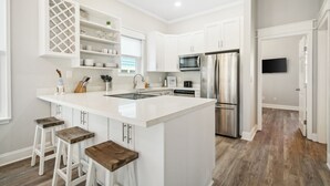 A modern kitchen with white cabinetry, stainless steel appliances, and a central island with bar stools. - Private Pool/Walk to the Beach/Sleeps10 (Panama City Beach)