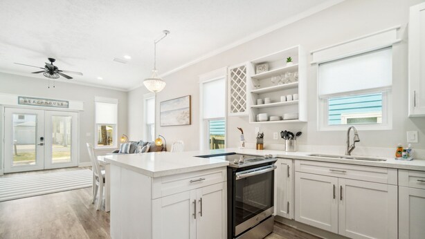 A modern kitchen with white cabinetry, a central island, a built-in oven, and a window with blinds. - Private Pool/Walk to the Beach/Sleeps10 (Panama City Beach)
