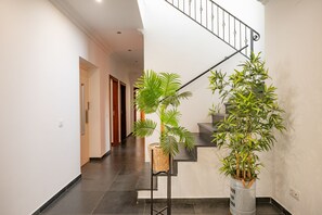 A staircase with a metal railing, a potted plant on the landing, and a hallway with a door at the end. - Your private retreat with garden, terraces, and stunning sunset views. (Estoi)