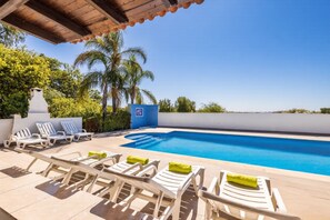 A poolside area with lounge chairs and a clear blue pool. - Your private retreat with garden, terraces, and stunning sunset views. (Estoi)