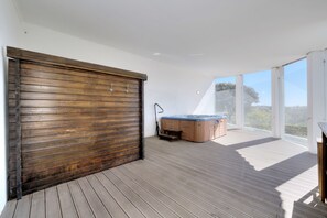 A spacious balcony with a hot tub, wooden flooring, and large windows offering a view of the outdoors. - Your private retreat with garden, terraces, and stunning sunset views. (Estoi)