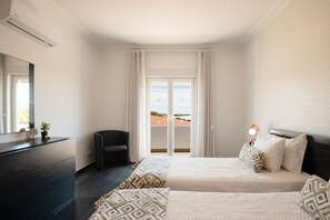 Ein Schlafzimmer mit einem Bett, einem Schminktisch, einem Stuhl und einem großen Fenster mit Vorhängen.