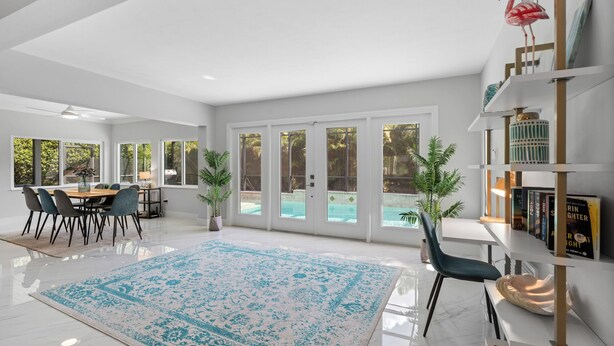 A spacious living room with a large window, a dining area, and a bookshelf. - Beautiful 2 bedroom bungalow in a quiet neighborhood (Fort Myers)