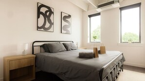 A modern bedroom with a bed, two bedside tables, and two windows. - Above The Roots - Stylish Square (Washington)