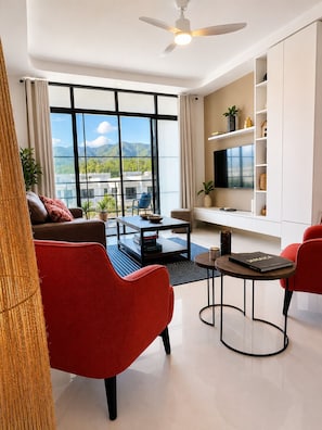 Ein modernes Wohnzimmer mit einer Couch, roten Sesseln, einem Couchtisch und einem Fernseher.