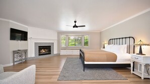 Un dormitorio con chimenea, cama, mesita de noche, televisor y ventilador de techo.