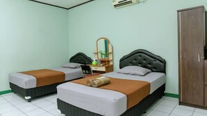 A hotel room with two beds, a desk, a mirror, and a wardrobe. - Hotel Antik (Soreang)