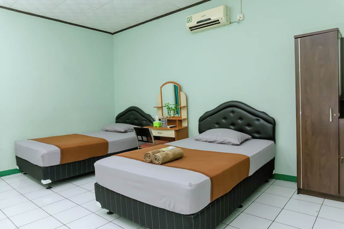 A hotel room with two beds, a desk, a mirror, and a wardrobe.