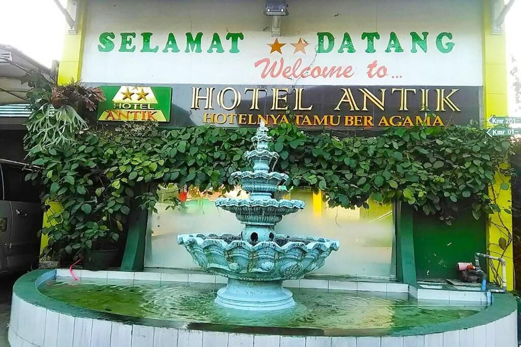 A hotel sign with a fountain in front.