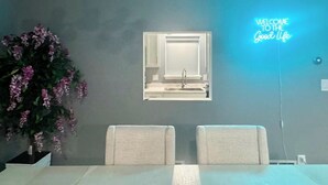 Ein modernes Badezimmer mit einer Neonreklame, einem Spiegel und einer Topfpflanze.