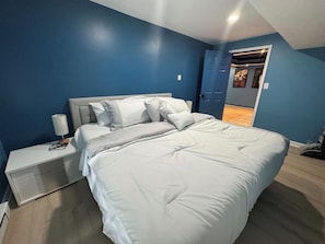 Une chambre à coucher avec un lit, une table de chevet et une porte donnant sur une autre pièce.