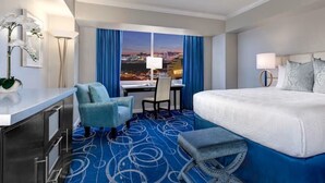Ein Hotelzimmer mit Bett, Schreibtisch, Stuhl, einem kleinen Tisch und Blick auf eine Stadtlandschaft.